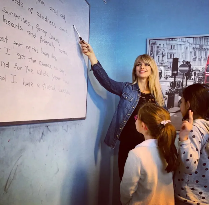 L'insegnante indica una poesia in inglese scritta alla lavagna a due bambine